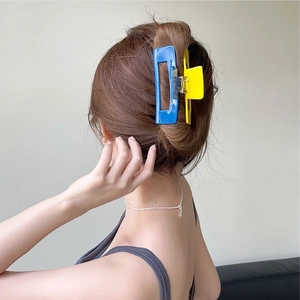 Rear view of model wearing a large blue and yellow contrast hair claw clip