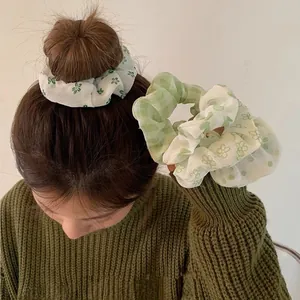 Dettaglio del set di elastici per capelli verdi a fiori e a quadretti tra i capelli