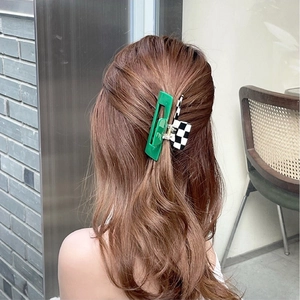 Detail of checkered and green acetate hair claw clip worn in a bun hairstyle outdoors