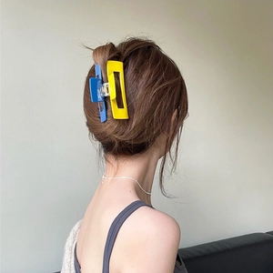 Macro view of blue and yellow matte large claw clips holding a neat hair bun style