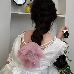 Détail d'un nœud à cheveux en dentelle rose à pois porté sur une tresse élégante