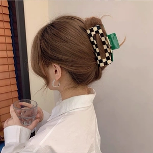 Detail view of large checkered hair claw clip with contrast green interior on model hair