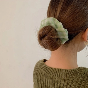 Dettaglio di un elastico per capelli a scacchi verdi su uno chignon castano