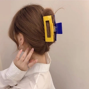 Detail view of large checkered acetate hair claw clips in vibrant yellow and blue colors