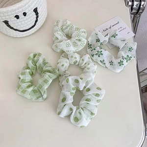 Dettaglio di elastici scrunchie verdi con motivi floreali e a scacchi