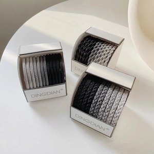 Detailed view of elastic hair ties set in black and gray tones with white packaging boxes