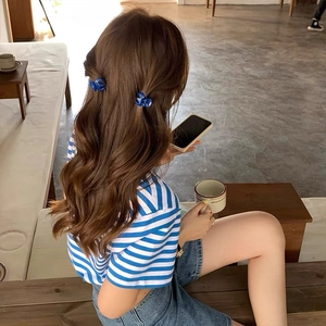 Mini navy blue butterfly hair clips styled on brunette wavy hair in a cafe setting