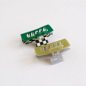 Detail view of large checkered acetate hair claws in matte green and olive tones