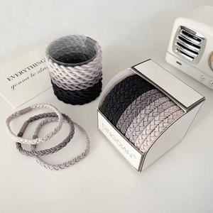 Close-up of high-elasticity braided hair ties in gradient grey colors with box