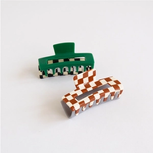 Detail of checkered acetate hair claw clips in green and brown on white background