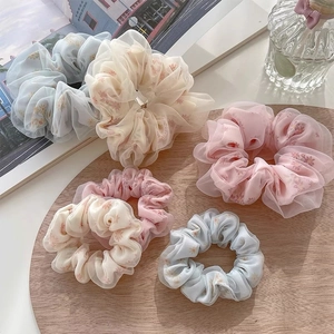 Chouchous en organza à fleurs aux tons pastel sur plateau en bois et magazine
