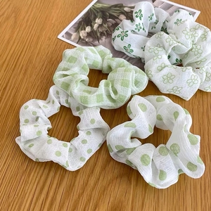 Dettaglio di quattro scrunchies verde chiaro con motivi floreali, a pois e a scacchi