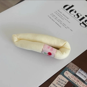 Détail d'un accessoire de cheveux en peluche jaune avec étiquette rose à motif cerise