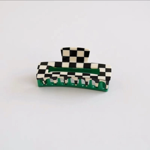 Detail of checkered acetate hair claw clip featuring green teeth and spring mechanism