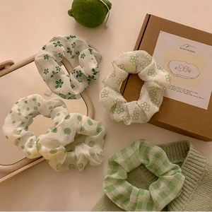 Dettaglio di quattro elastici per capelli in organza verde con motivi floreali