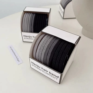 Detailed view of high-elasticity hair ties in a minimalist white gift box with soft lighting