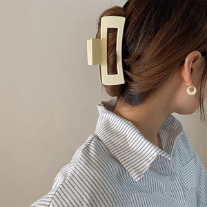 Detail of a large cream-colored matte hair claw clip on brunette hair for hair styling