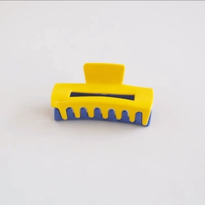 Detail view of large blue and yellow color-block hair claw clip with glossy finish