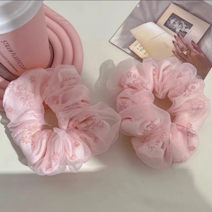 Détail de chouchous en maille rose à motifs floraux pour queues de cheval élégantes
