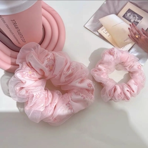 Détail d'un ensemble de chouchous en tulle rose avec des motifs floraux de marguerites