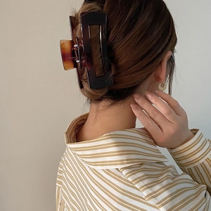 Macro view of a 12.5cm oversized tortoiseshell hair claw clip used in a bun hairstyle