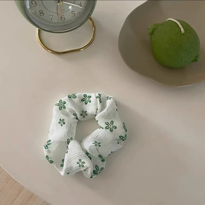 Dettaglio di elastico floreale con motivi verdi su tessuto bianco a pieghe sottili
