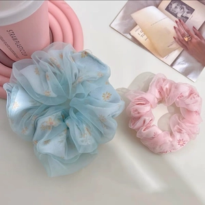 Gros plan sur des chouchous en résille avec motifs marguerites jaunes en rose et bleu
