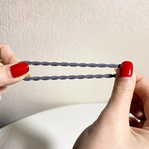 Close-up of high-elastic spiral hair tie showing durable dark gray woven texture