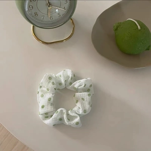Vista dettagliata di un elastico per capelli in tessuto bianco con pois verdi
