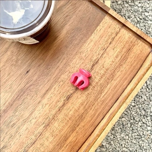 Outdoor close-up of a small glossy pink hair claw clip placed on a wooden tray