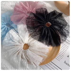 Détail de quatre chouchous en tulle à pois sur plateau en bois avec texture dentelle