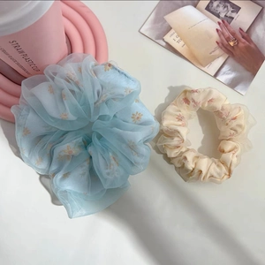 Détail macro de chouchous en maille florale bleu ciel et beige en organza doux