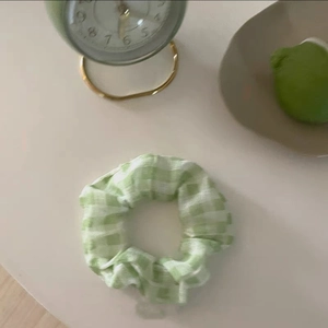 Dettaglio di un elastico per capelli a quadretti verdi e bianchi in morbido cotone