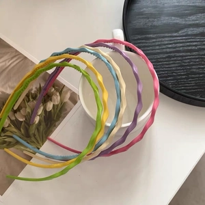 Set of six colorful wave shaped skinny headbands in vibrant candy tones on a ceramic cup
