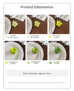 Gros plan de petites pinces à cheveux fleur en six nuances de vert sur assiettes blanches