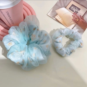 Détail de chouchous en tulle bleu clair avec motif de marguerites en deux tailles