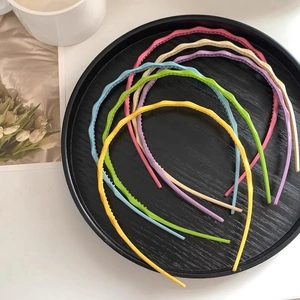 Close-up of wavy candy-colored headbands with non-slip teeth on a dark tray