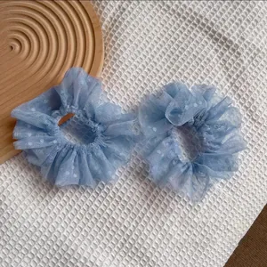 Gros plan de chouchous en dentelle bleu clair à pois blancs sur un fond texturé