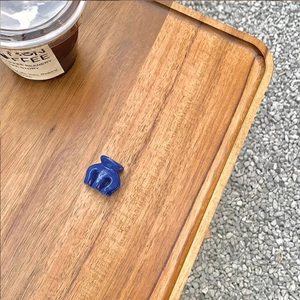 Detail of a mini dark blue glossy hair claw clip on a rustic wooden tray for women
