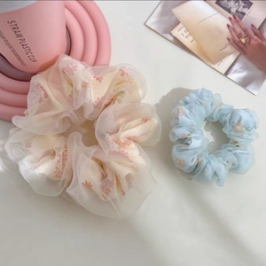 Détails de deux chouchous en tulle à fleurs dans des tons pastels rose et bleu ciel