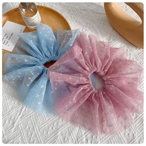 Gros plan sur des chouchous en dentelle bleu ciel et rose avec maille à pois et volants