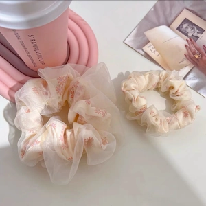 Détail de chouchous surdimensionnés en organza et motif floral blanc crème et rose