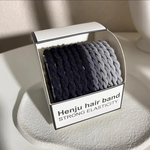 Close-up of high elasticity hair ties in gradient grey and black woven texture box