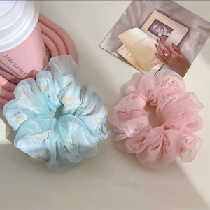 Gros plan détaillé de grands chouchous en organza pastel avec des motifs de marguerites