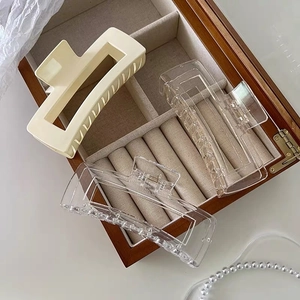 Macro shot of large matte cream and transparent hair claws in a wooden velvet box