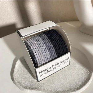 Detail of high elasticity hair bands in gray and black tones inside a minimalist display box