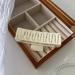 Detailed view of cream rectangular matte hair claw clip on wooden jewelry box