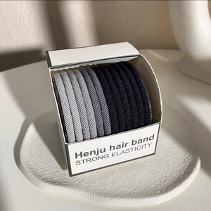 Close-up of high elasticity hair bands in black and grey tones within a minimalist box