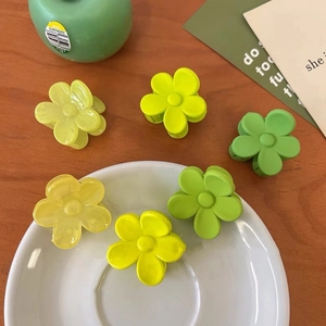 Détail de pinces à cheveux en forme de fleur jaune et vert melon sur une table en bois