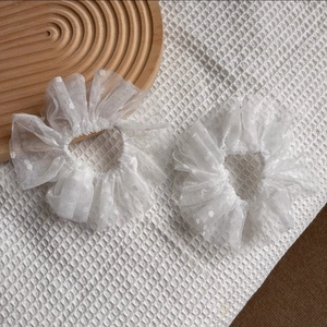 Détail de chouchous en dentelle blanche avec texture en maille plissée et motif à pois